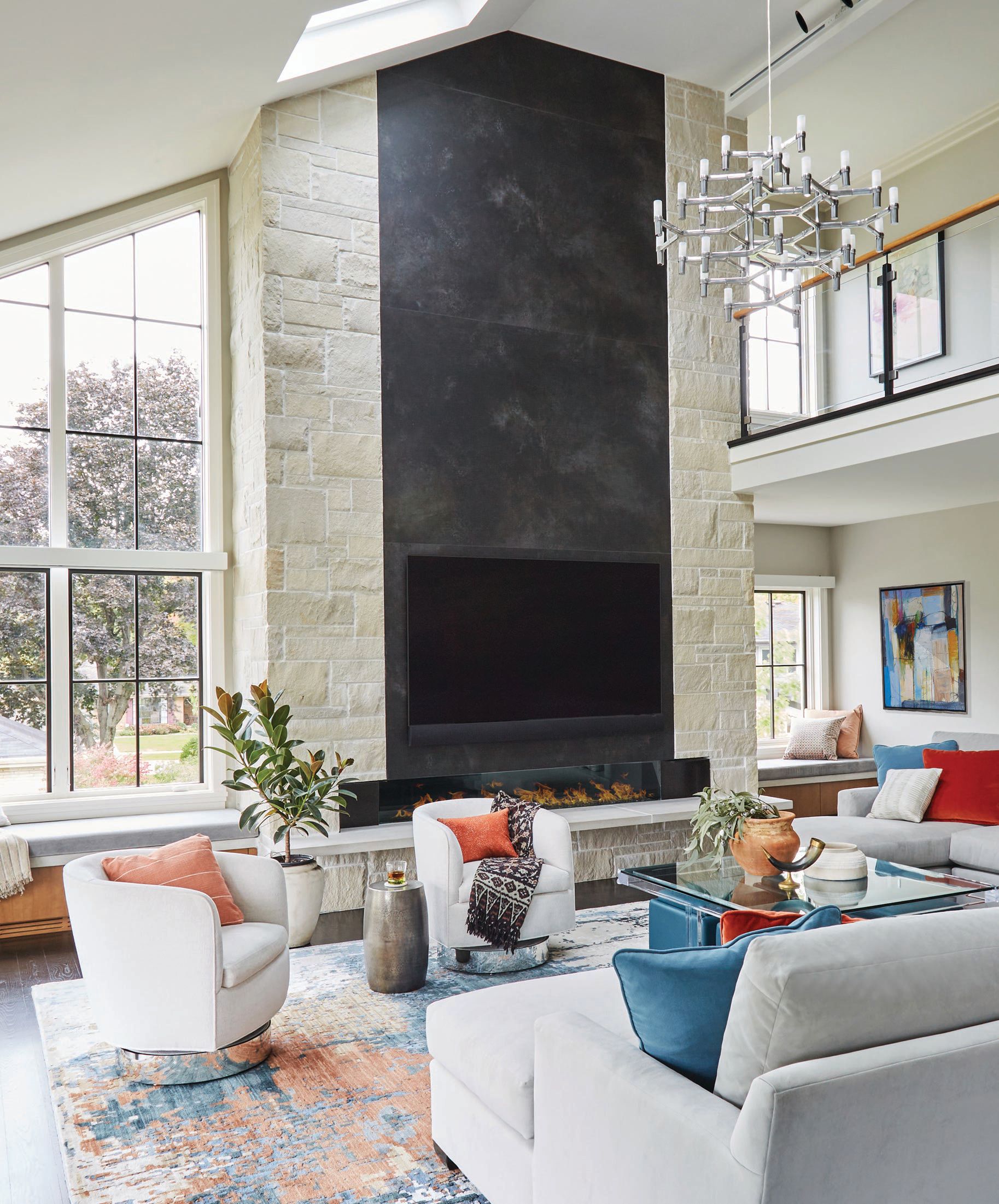 The soaring family room is anchored by a Crown Major chandelier in polished aluminum from Lightology, sleek swivel chairs by Thayer Coggin, a sofa by Century Furniture and a coffee table by Kravet. Photographed by MICHAEL ALAN KASKEL