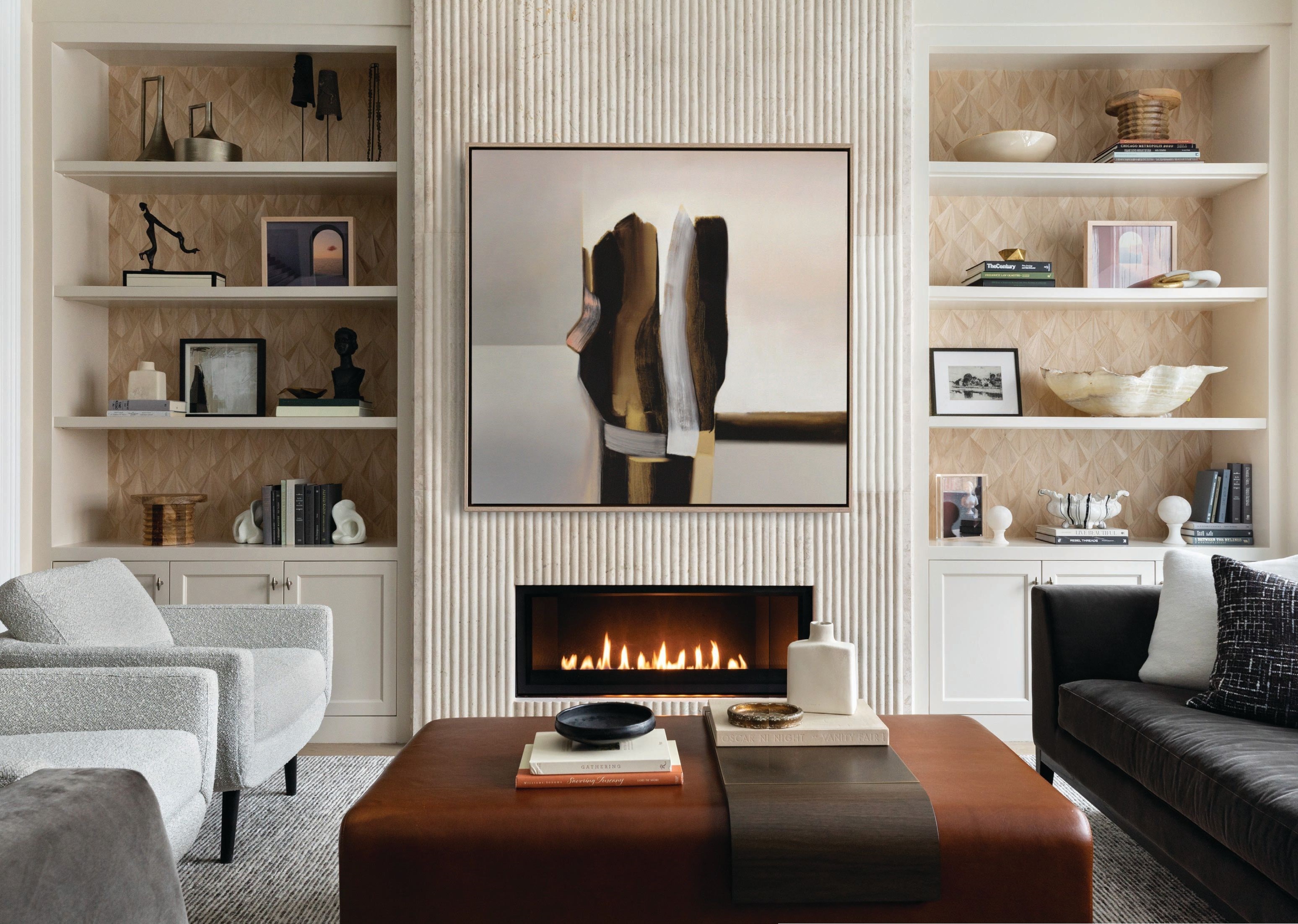 The family room features a custom Lumifer cocktail ottoman/table covered in ginger leather from Keleen Leathers, plus one of the project’s pièces de résistance: a showstopping custom fireplace that runs the full height of the wall designed by Donna Mondi Interior Design and fabricated by Material Bespoke Stone   Tile. Photographed by Aimée Mazzenga
