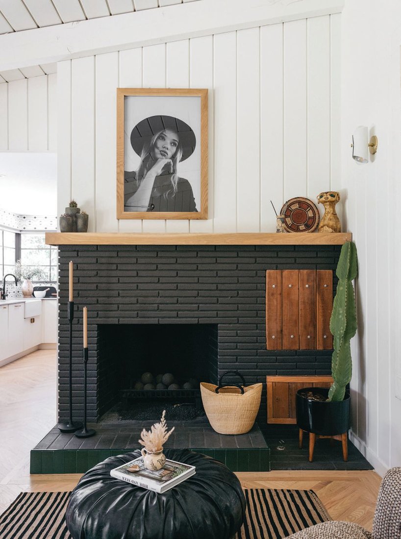 The fireplace nook features a piece sourced from Saatchi Art. “The striking, bold color of the fireplace ties in nicely with the black window trim,” says designer Kirsten Blazek. “The white oak mantel beautifully offsets the dark paint.” PHOTOGRAPHED BY ALEX ZAROUR, VIRTUALLY HERE STUDIOS