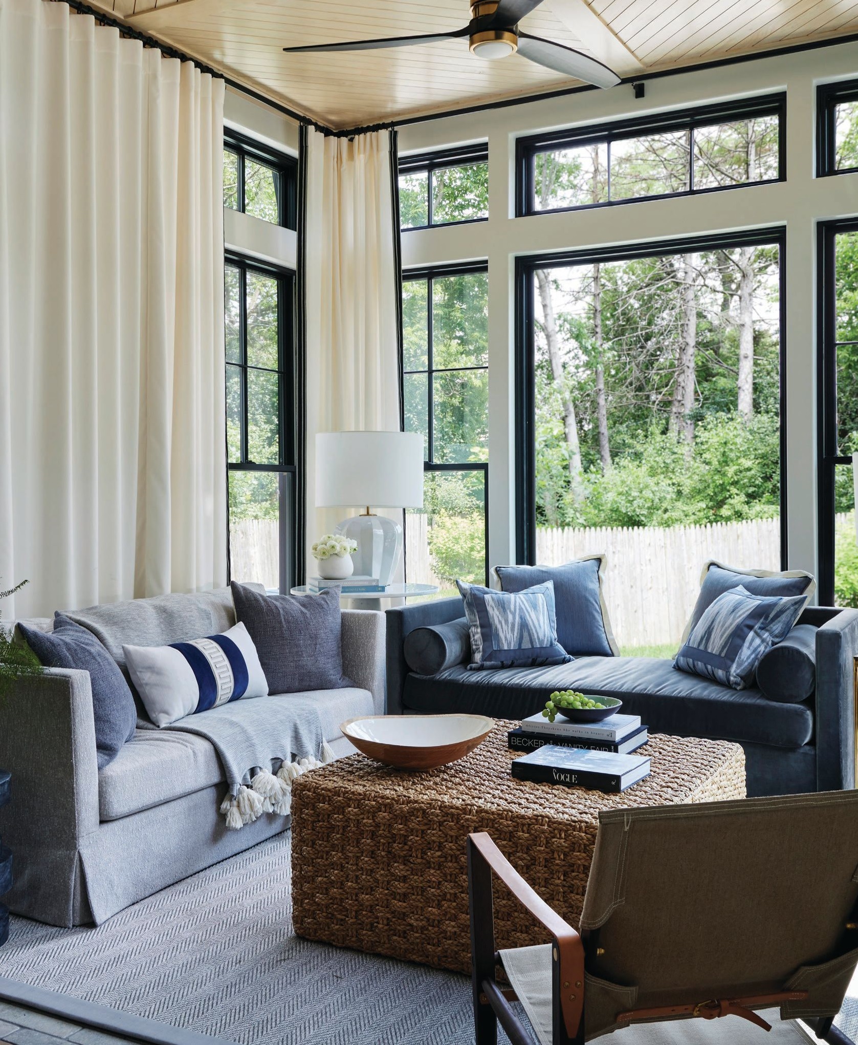 A custom skirted sofa upholstered in Sand Drift outdoor fabric by Holly Hunt and a seagrass coffee table by Palacek highlight the airy sunroom. Photographed by Werner Straube