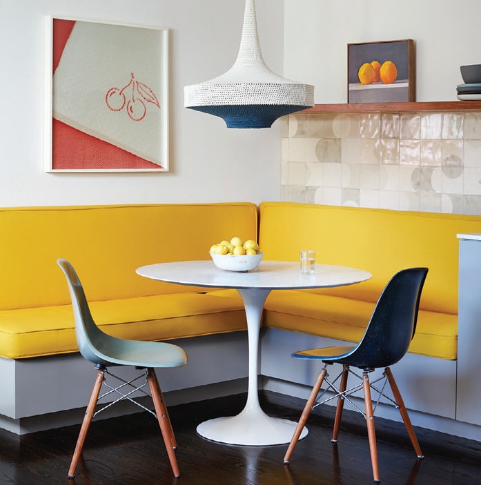 In the kitchen, a dining banquette covered in sunny Maharam fabric surrounds a Saarinen table Photographed by Trevor Tondro