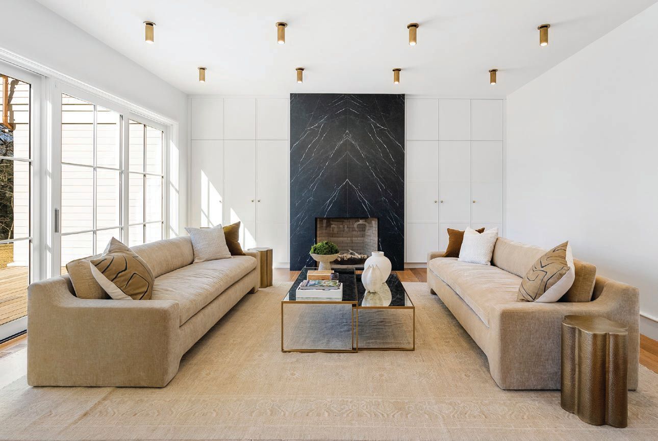 The black floor-to-ceiling marble fireplace perfectly contrasts with the white living space. PHOTO BY DRONE HOME MEDIA