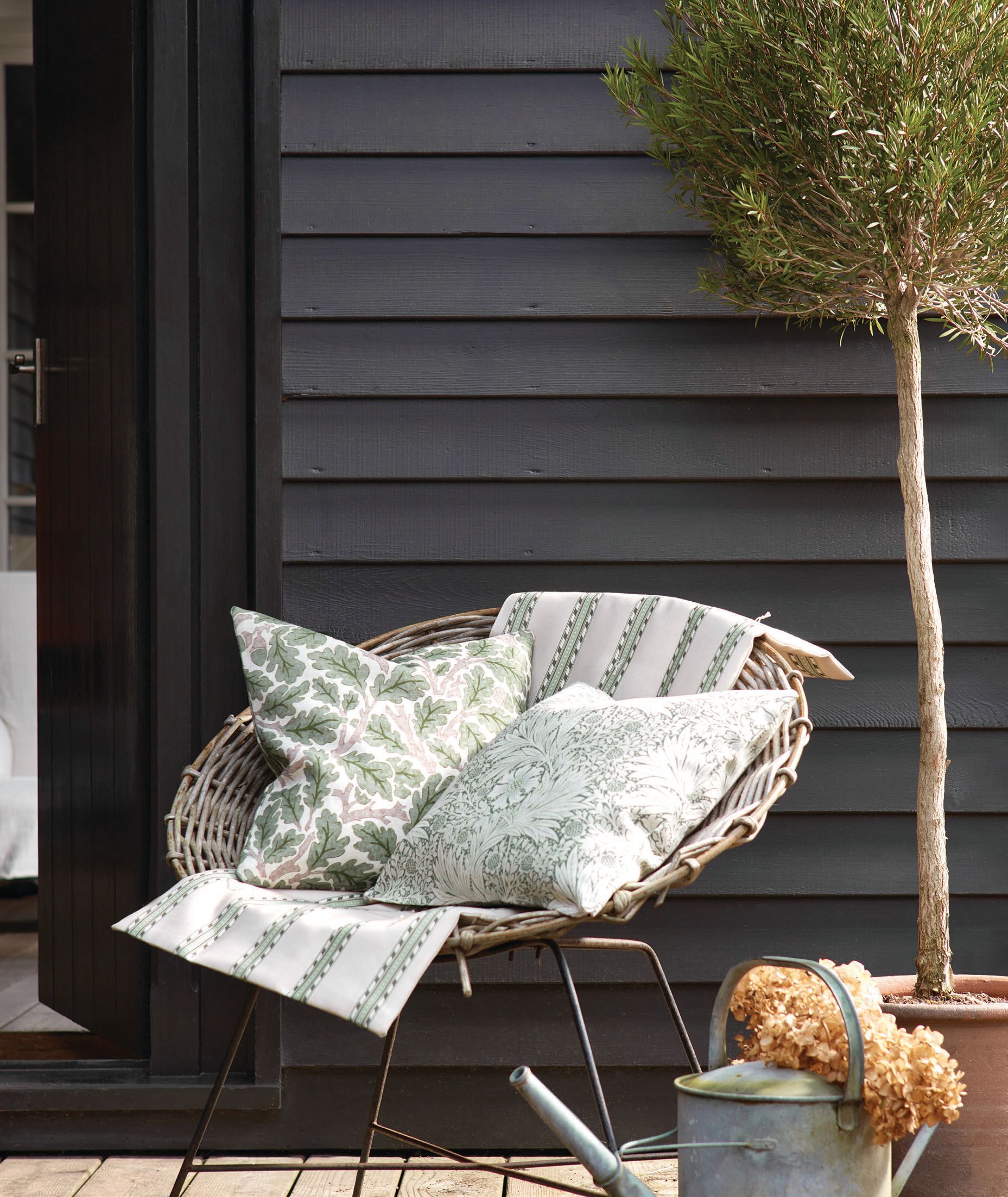 Pillows in Morris & Co. outdoor/performance collection fabrics Oak in sage green and Marigold in Mineral Blue atop a throw in Holland Park Stripe in sage and linen PHOTO COURTESY OF SANDERSON DESIGN GROUP