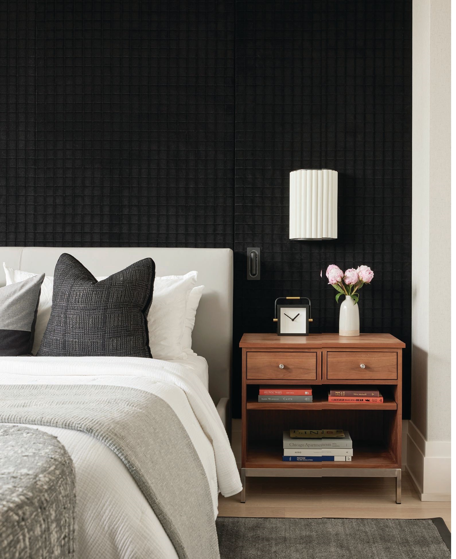 The primary bedroom is a stunner thanks to a coal-colored wall upholstered in Pollack’s Embellushed Plush Photographed by Mike Schwartz