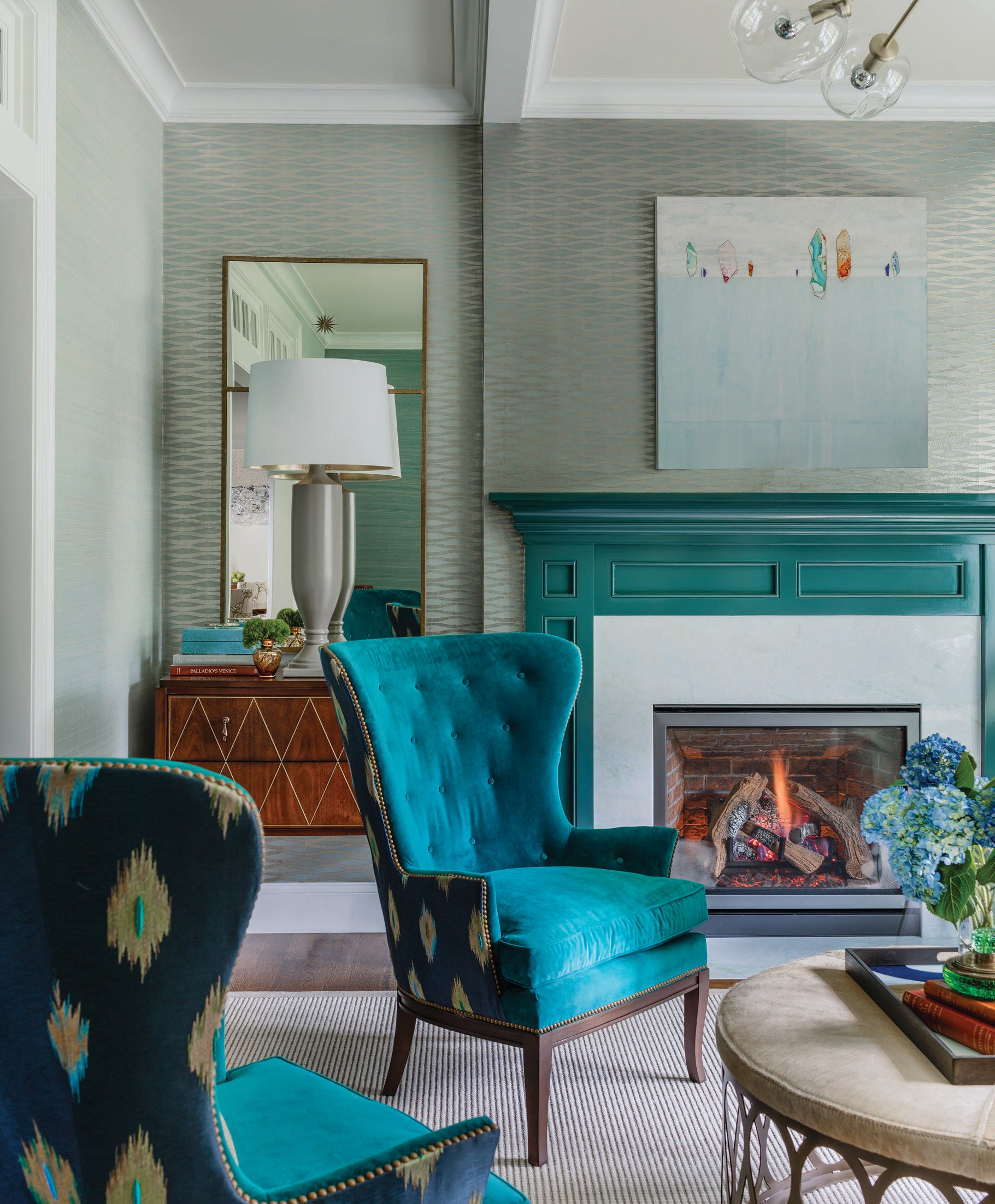 Phillip Jeffries wallpaper adds texture behind the roaring fireplace in the living room, while a simple Jules Place painting lords over the space. Photographed by Michael J. Lee
