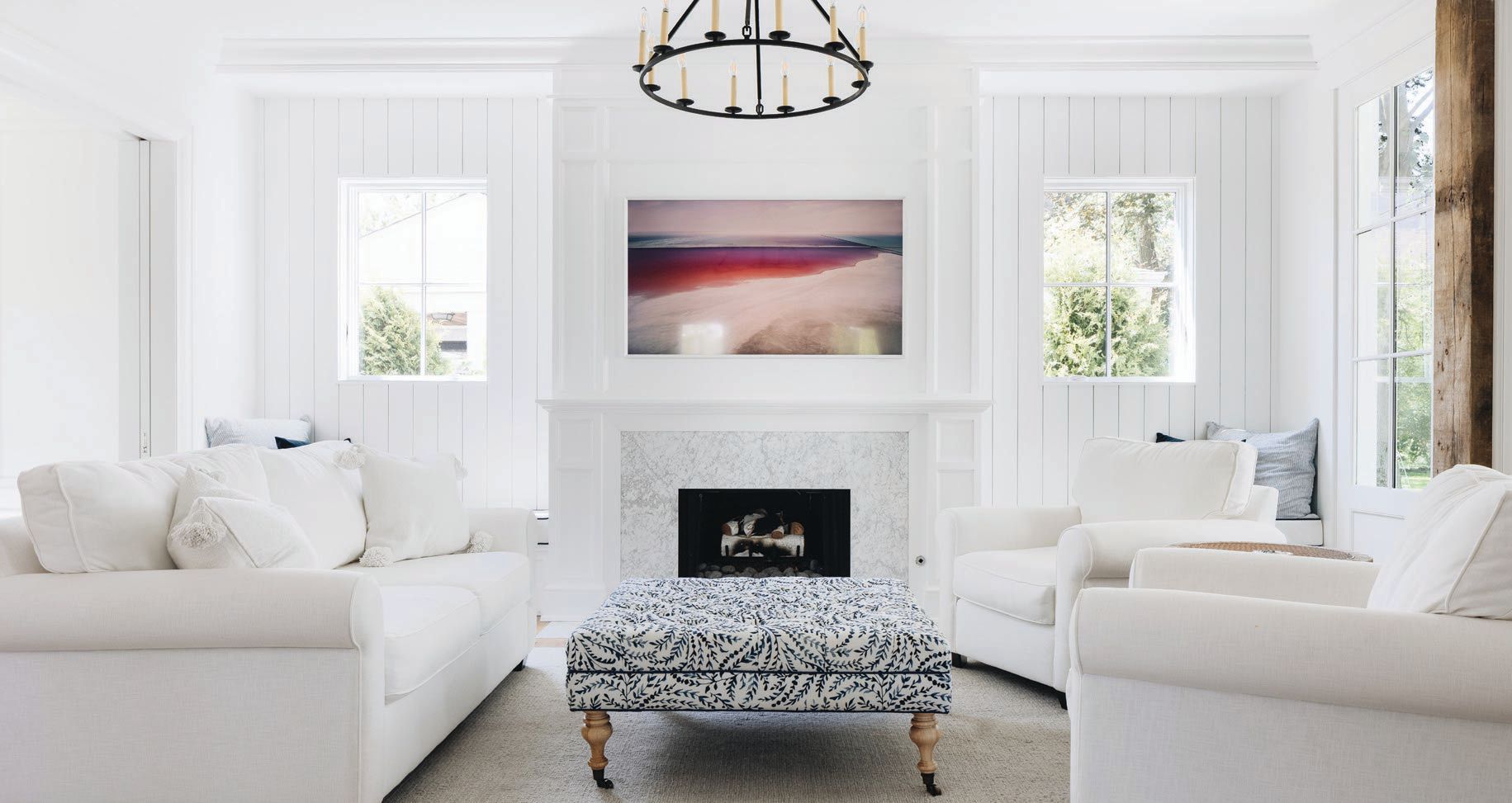 This North Shore gem by Scott Simpson Design   Build features a light, bright living area with a white marble fireplace surround, a TV that doubles as artwork, texture-rich panel molding and a dramatic focal light fixture. STOFFER PHOTOGRAPHY