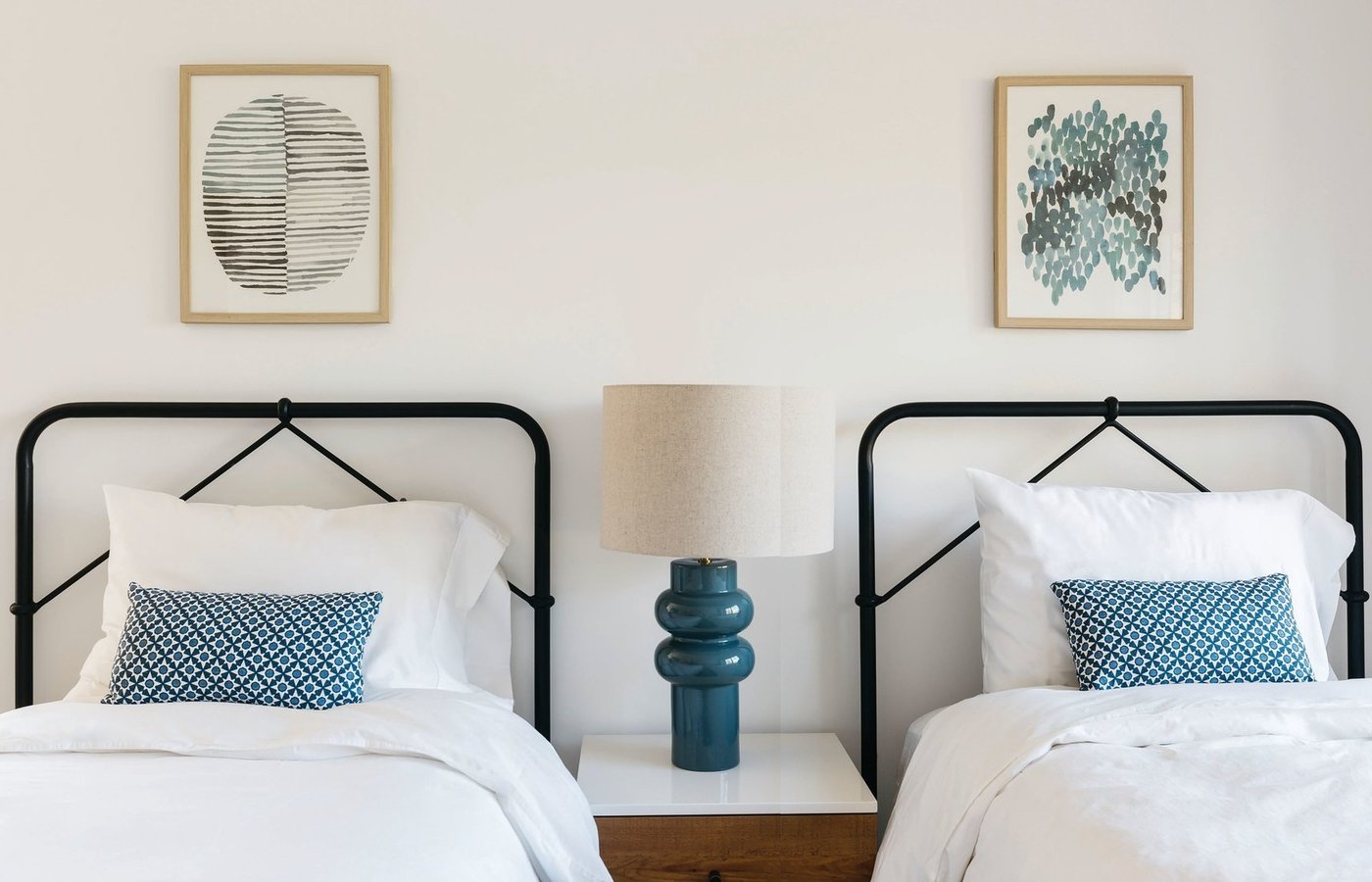 In a guest room, Lisac paired twin iron beds by Four Hands with decorative pillows upholstered in Schumacher fabric. PHOTOGRAPHED BY MARGARET AUSTIN PHOTOGRAPHY