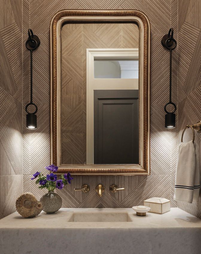 The powder room pops with Porcelanosa’s Minnesota Moka tile and linear bronze downlight sconces from 1stDibs. Photographed by Werner Straube