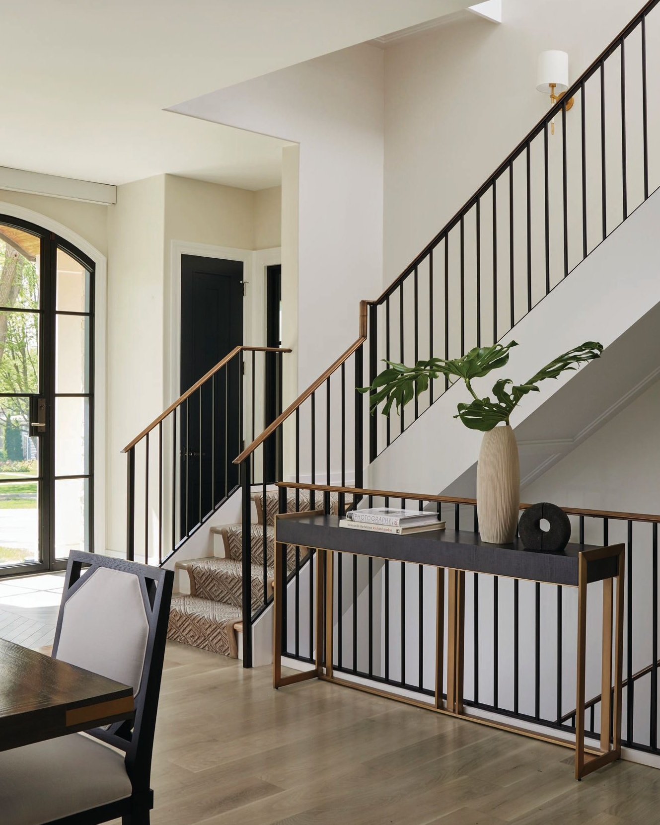 The foyer features 7-inch white oak floors by Apex Flooring and a black iron stair railing by Step 1 Stairworks. Photographed by Werner Straube
