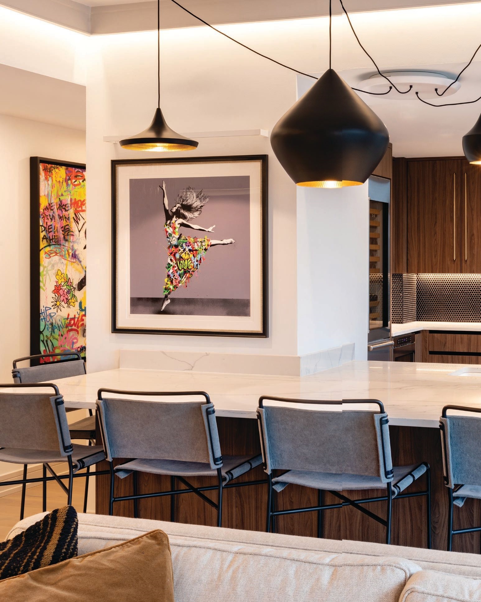 The secondary kitchen pops with Martin Whatson’s artwork “Dancer,” a Beat Range round multi-light LED pendant light and Perkins bar and counter stools by Pottery Barn, with an original artwork by Onemizer visible in the hallway. Photographed by Kyle Flubacker