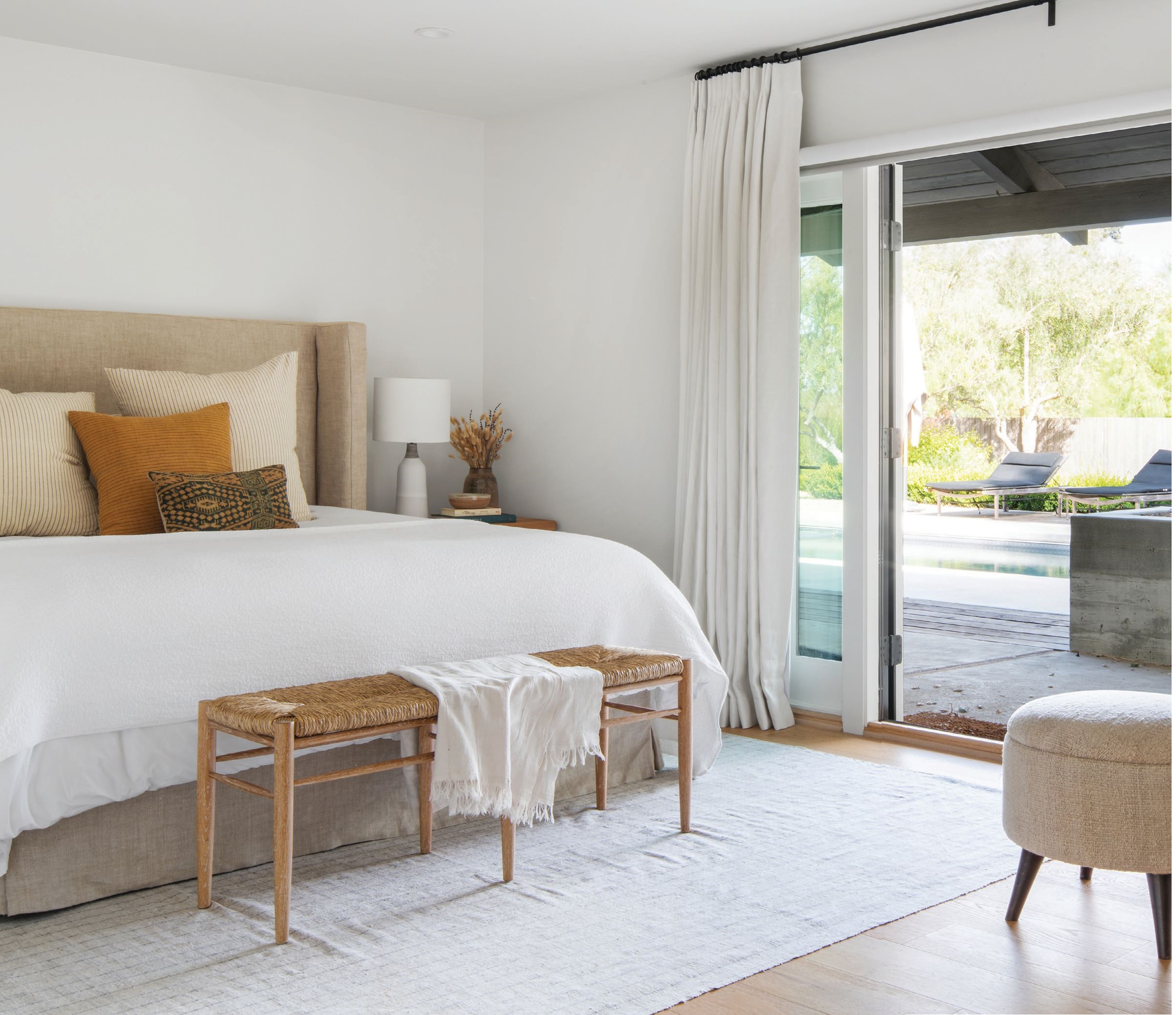 Located just off the pool, a guest bedroom is accented with a bench from Made
Goods, nightstands by Nickey Kehoe and bedding by Parachute Home. The pillows and rug are vintage. PHOTOGRAPHED BY GAVIN CATER