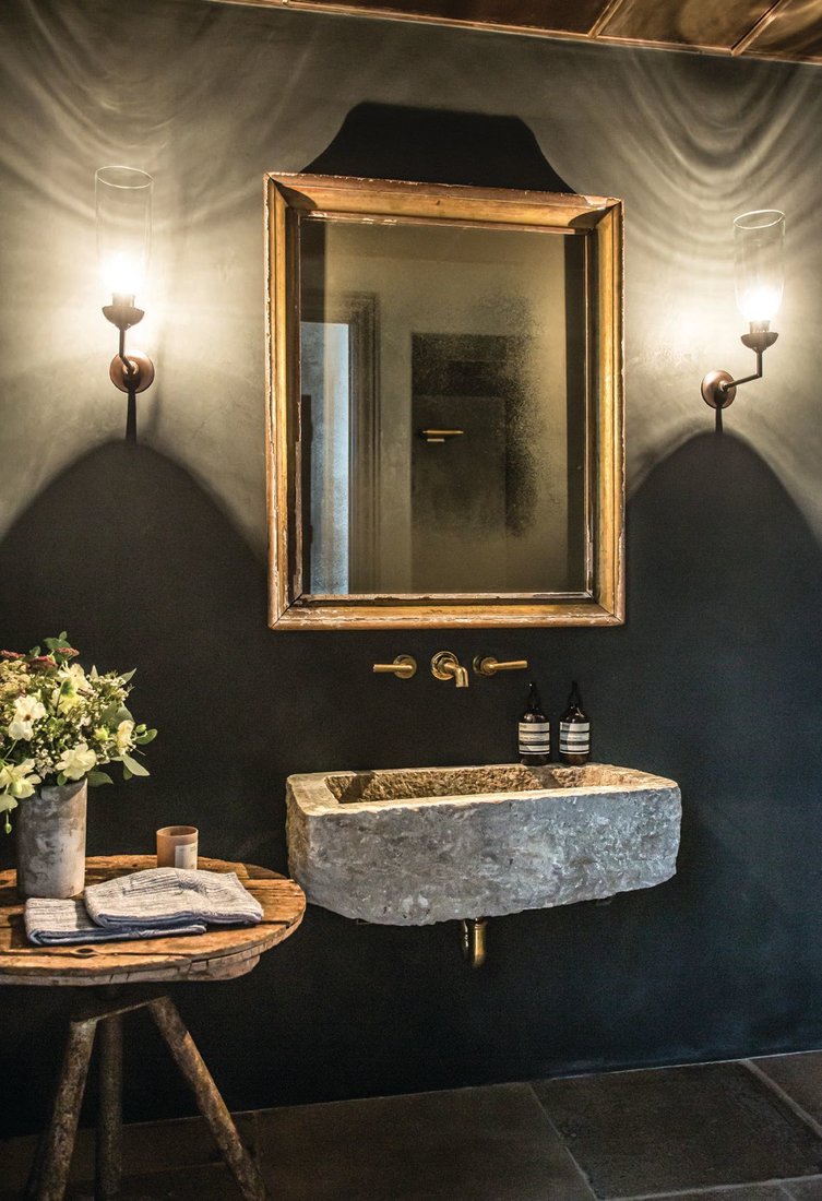 Roman Clay paint sets the mood in this glamorous bathroom by Studio Jake Arnold, while a sink from Berbere Imports, a Rose Uniacke sconce, a side table from Obsolete, a Waterworks faucet and a mirror from Galerie Half add an earthy, curated touch. PHOTO BY MICHAEL CLIFFORD.