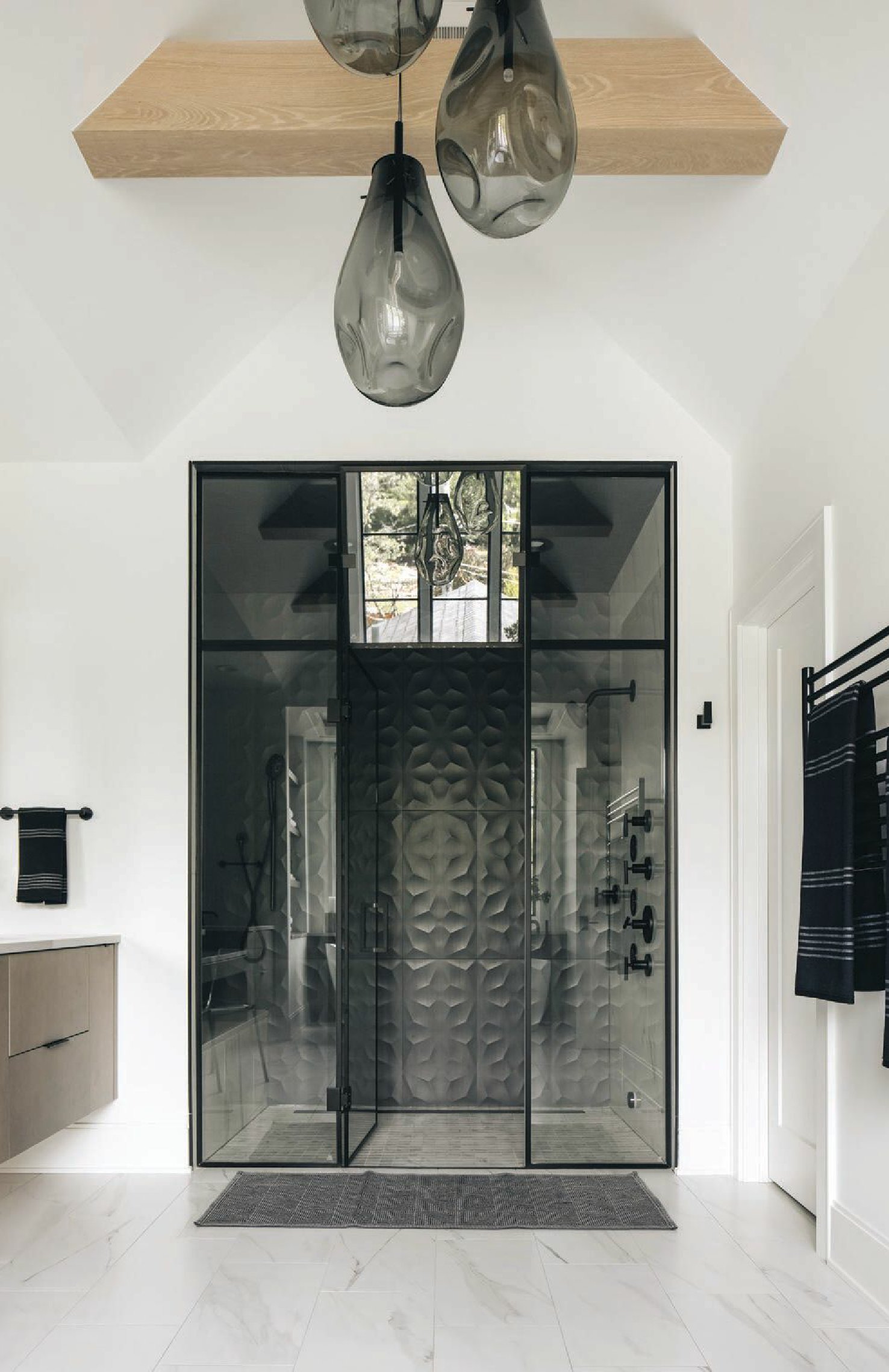 In the primary bath, dramatic lighting by Sonneman and glam 3D wall shower tile in Night Diamond by Virginia Tile set a sultry scene. Photographed by Stoffer Photography Interiors