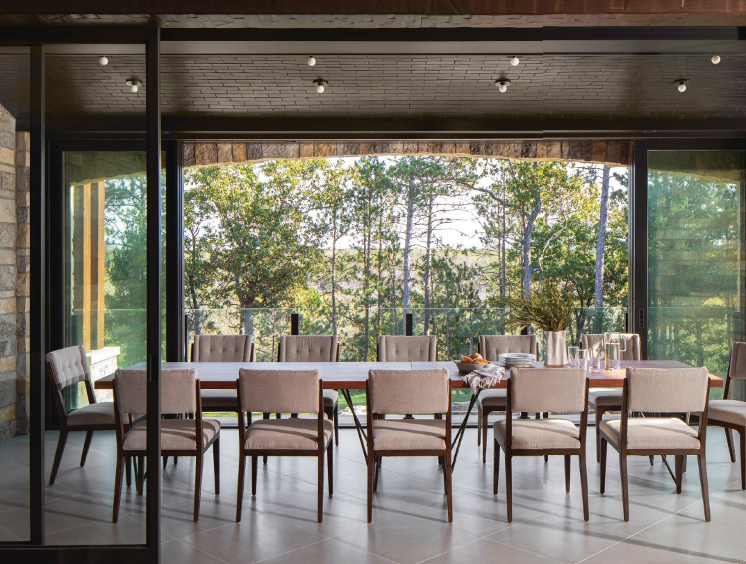 In the dining room, the muted tones of CB2’s Dylan table in acacia wood, chairs by Baker Furniture and Waterworks Taurus 2 tile allow the magnificent view of the woods to take center stage Photographed by Ryan Hainey