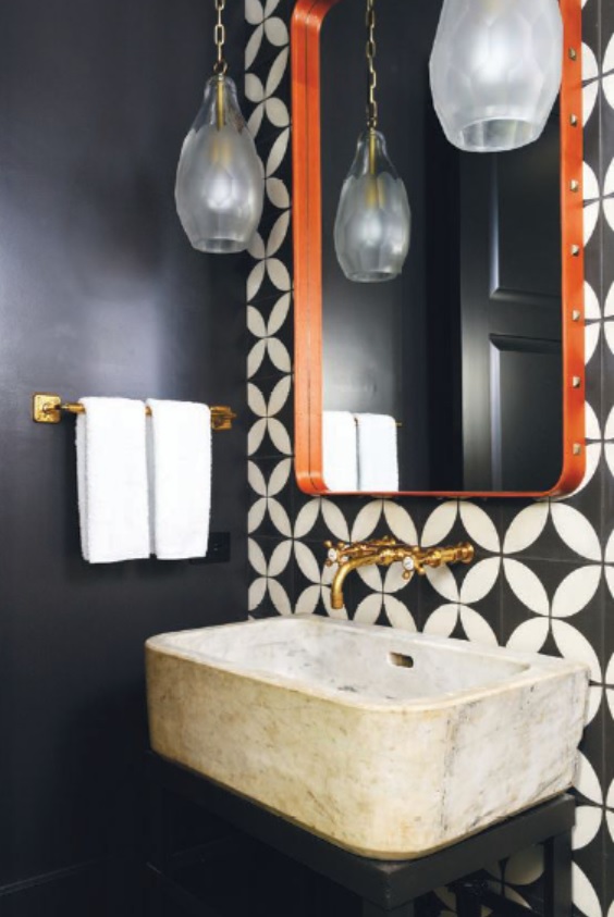 In this powder room find patterned ceramic tiles, a carved stone sink, wall-mounted brass plumbing fixtures and hardware. PHOTO BY: CHRIS EDWARDS